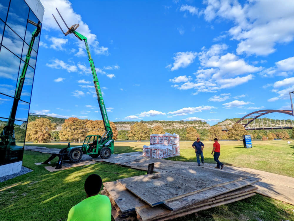 A boom lift raising roofing material up on a commercial roofing job.