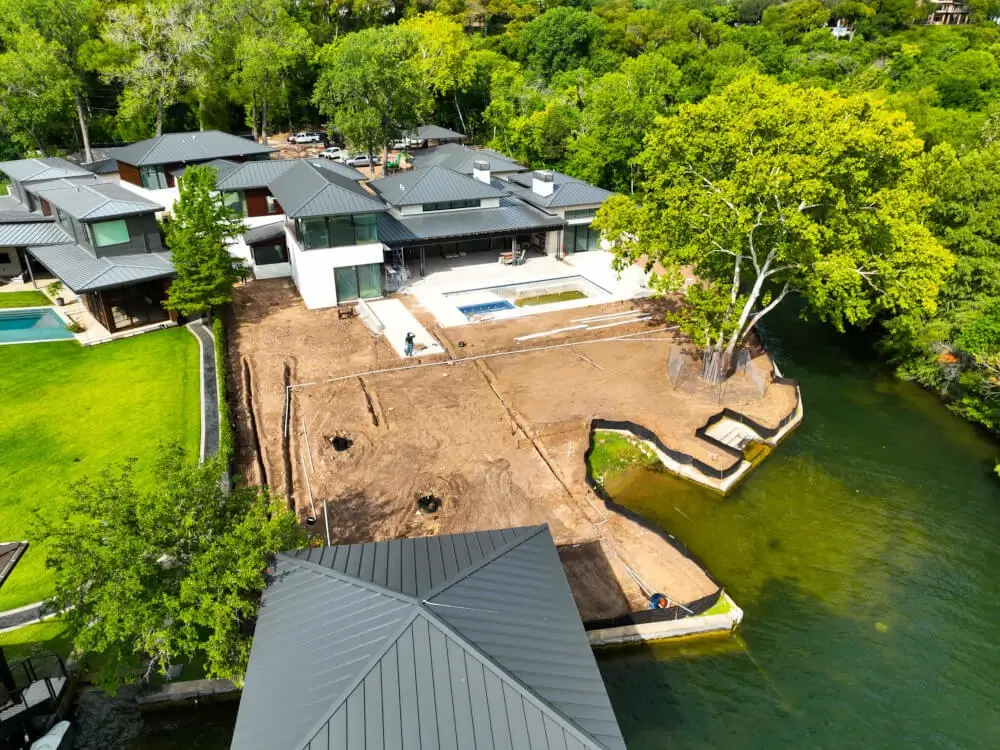 A new home under construction by the water with roofing materials installed by Texas Roof Repair.